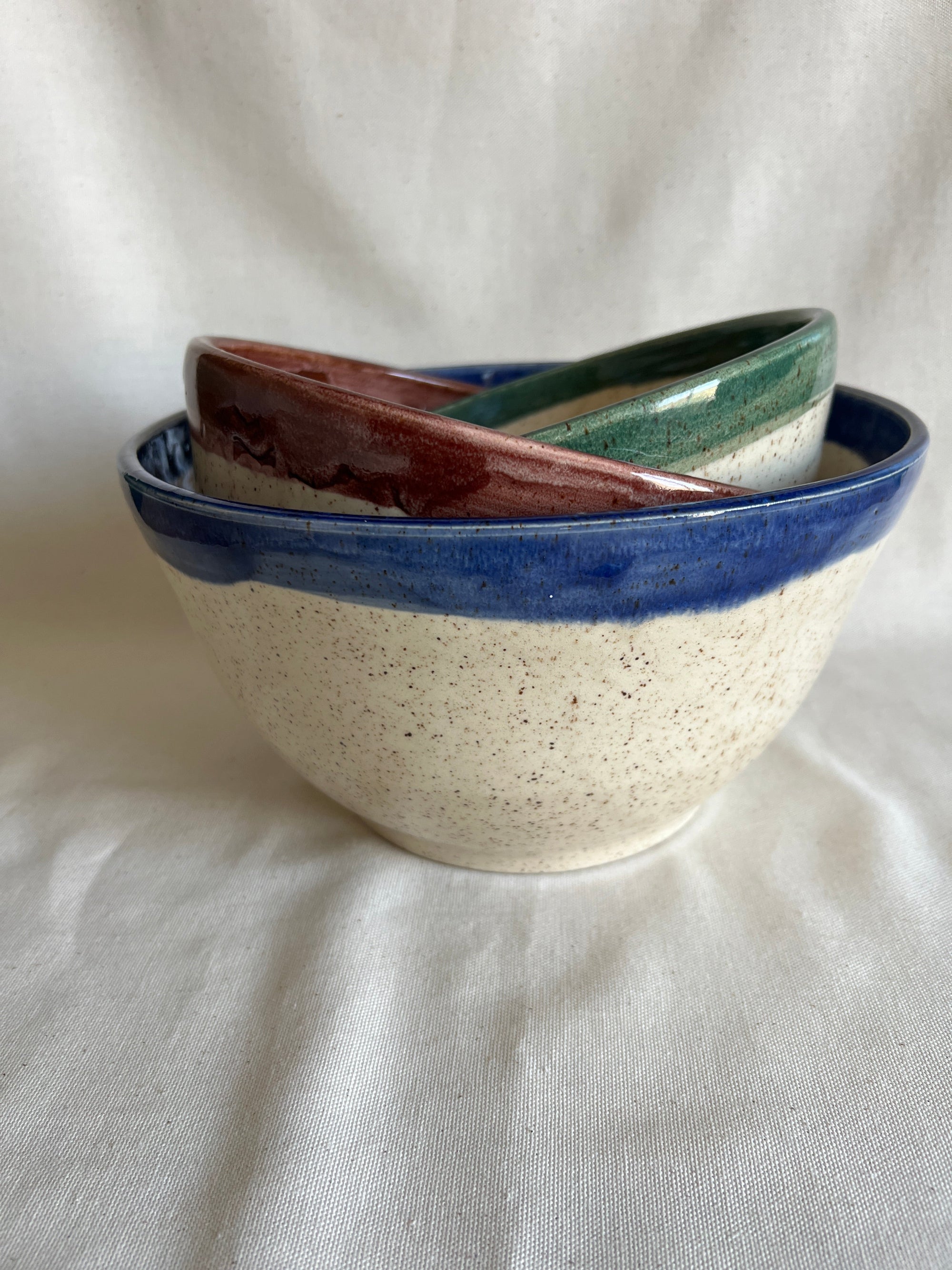 Ceramic bowl with multicolored rim on a white fabric background